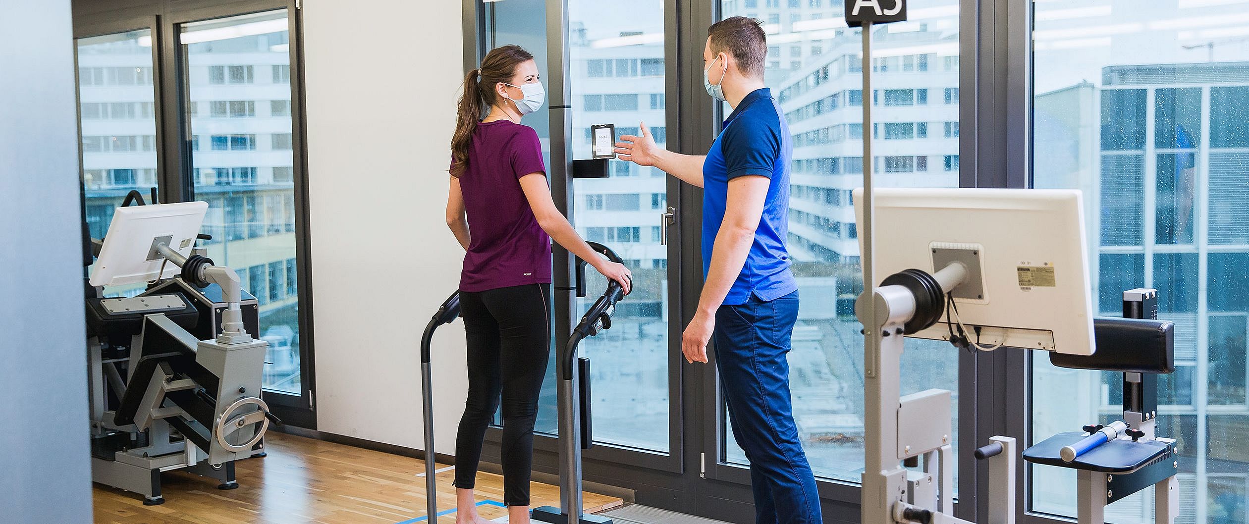 Das Bild zeigt einen Kieser-Kunden, der von einem Trainer bei einer BIA-Messung begleitet wird. Die BIA ist eine Körperwaage, die Muskel- und Fettmasse misst.